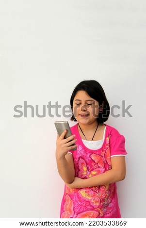 10-year-old Hispanic girl uses her cell phone to make video calls, play video games, send messages, take photos, selfies, watch and record videos as an influencer and have fun in her free time