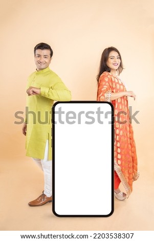 Happy Young Indian Couple Standing With Big Smartphone Blank Screen, App Or Website Design, Standing Over beige  Background, Online Shopping, Mockup, Technology, Festive offer and sale, Copy Space,  Royalty-Free Stock Photo #2203538307