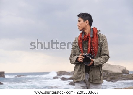 A tourist with a backpack on his back stands against the backdrop of a beautiful seascape