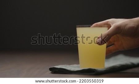 man hand take lemonade in tumbler glass from wood table with copy space, wide photo