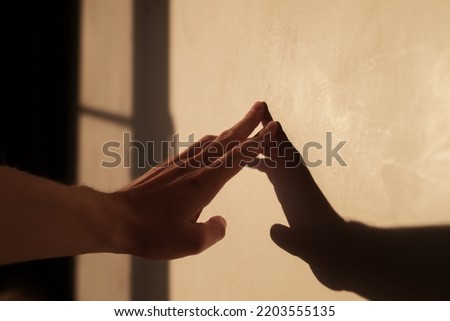 Abstract man hand touch wall with sunset light and long shadows, shallow focus