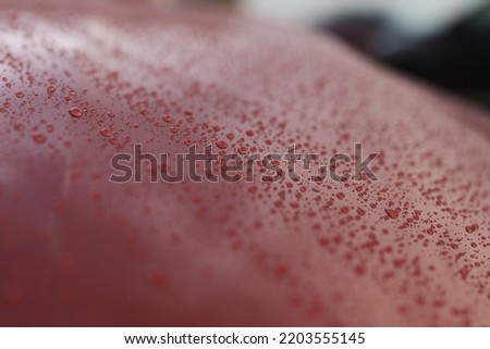 Wet red car with hydrophobic coating, shallow focus