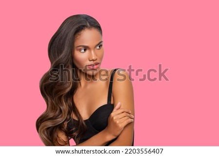 Fashion model Brunette with long curly Hair, with perfect makeup. Beautiful stylish African model on colored background.                        Royalty-Free Stock Photo #2203556407