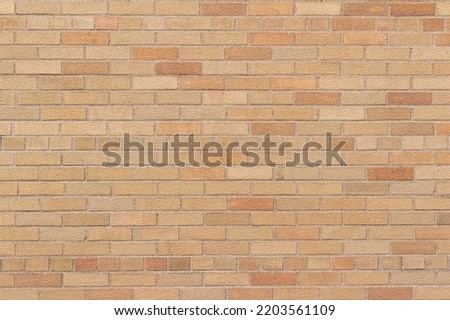 Full frame abstract texture background of an grungy vintage brick wall in a common bond brickwork pattern, with bricks in varying shades of orange and beige