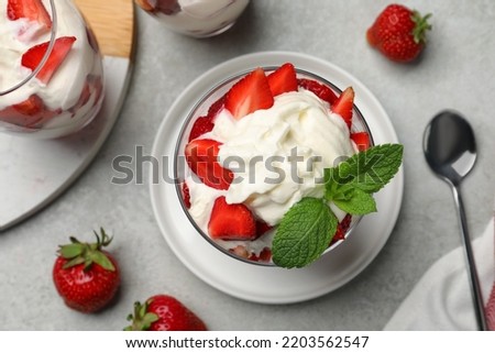 Delicious strawberries with whipped cream served on light grey table, flat lay Royalty-Free Stock Photo #2203562547