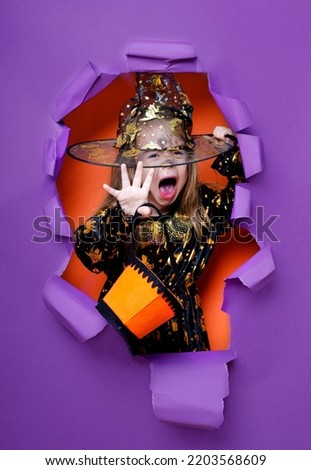 Laughing funny child girl in a witch costume in halloween