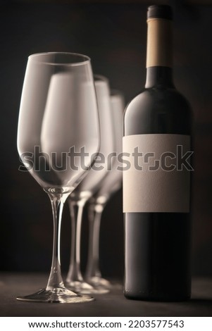 wine glasses and a bottle of red wine with a white label without an inscription. Beautiful soulful still life, dark background atmospheric mood
