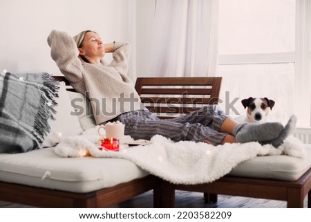 Full length calm middle aged woman with closed eyes resting on cozy couch, leaning back, enjoying lazy leisure time, attractive peaceful 40s female relaxing, daydreaming, taking nap on sofa at home
