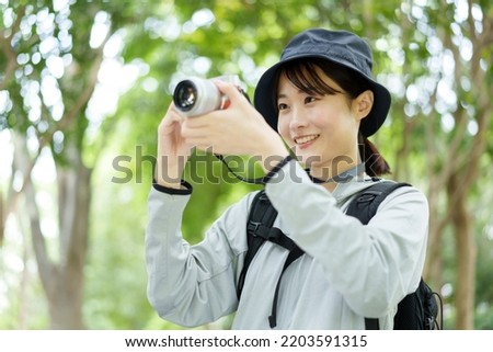 attractive asian woman holding digital camera trekking in forest