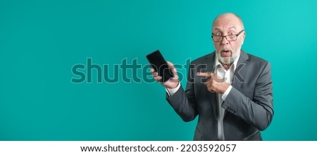 Application advertising. Adult man in glasses showing black blank smartphone screen recommending website posing in studio green background