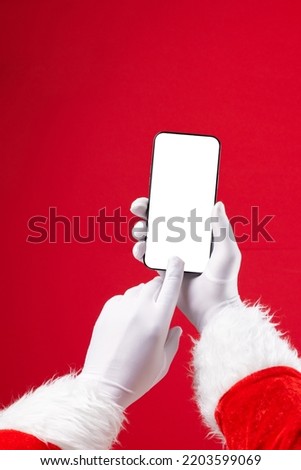 Image of hands of santa claus holding smartphone with blank screen and copy space on red background. Christmas, connection, technology, tradition and celebration concept.