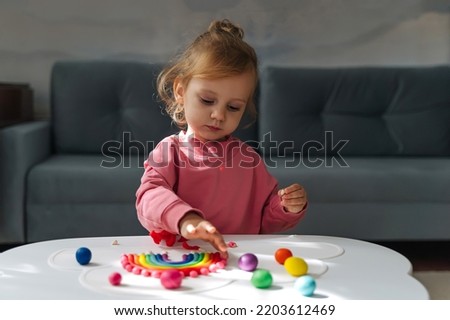 A little girl playing with rainbow from play dough for modeling. Art Activity for Kids. Fine motor skills. Sensory play for toddlers.	 Royalty-Free Stock Photo #2203612469