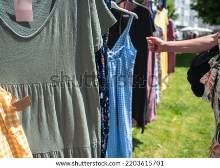 Arm of a 40-year-old woman looking at dresses in a flea market