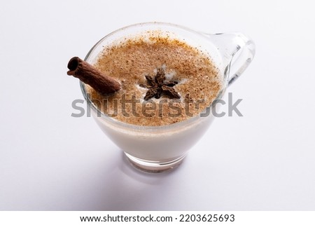 Image of glass of christmas milk with cinnamon stick, anise star and copy space on white background. Christmas, tradition and celebration concept.
