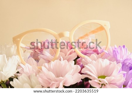 trendy beige plastic eye glasses and flowers, fashion eyewear conccept, creative shoecase