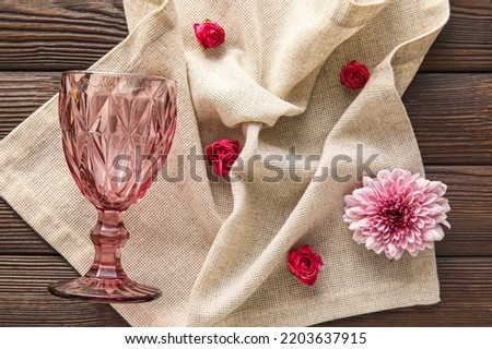 Overturned glass, napkin and flowers on dark wooden background