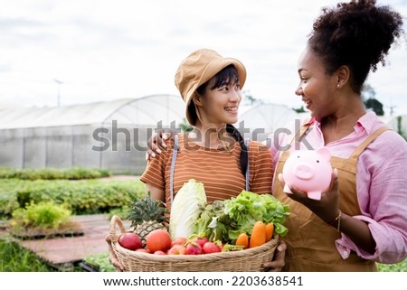 Basket with vegetables. Couple farmer woman holding wooden box full of fresh raw vegetables for sale in the local farm or green house. Saving money by piggy bank