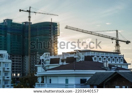 Modern big multi-storey residential or office high rise building under construction, sunrise sky background, tower cranes. Real estate business, buying investing in apartments abroad, mortgage