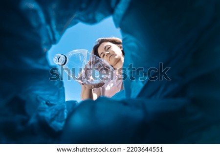 A woman throws a plastic bottle into the trash. Close-up from inside the trash can Royalty-Free Stock Photo #2203644551