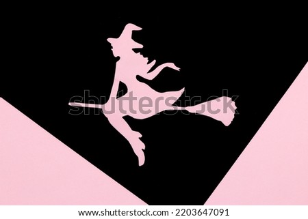 witch on broom on black part of black and pink background, creative art design, halloween minimal concept