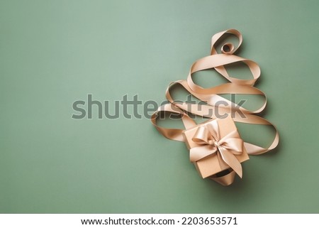 New Year card with concept of Christmas tree made of golden ribbon and gift box on olive background.