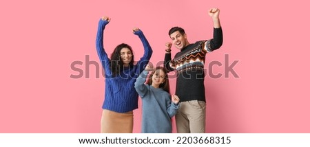 Happy family in warm sweaters on pink background