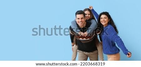 Happy family in warm sweaters on blue background with space for text Royalty-Free Stock Photo #2203668319