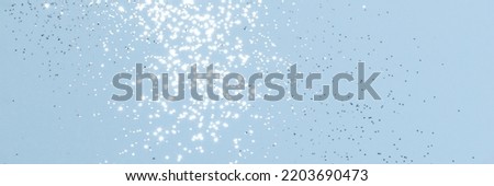 Sparkling silver glitter on blue background banner texture. Abstract holiday blurred lights header. Wide screen wallpaper. Panoramic web banner with copy space for design