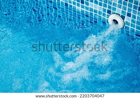 Top view of an active underwater discharge nozzle filtration system set in a blue liner swimming pool with low water level ready for winter. Royalty-Free Stock Photo #2203704047