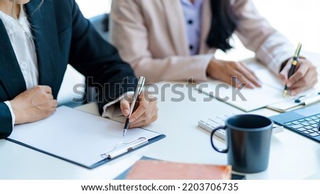 Close-up of business people taking note at a meeting on clipboard for drafting, writing meeting minutes in office and printing on computer. Royalty-Free Stock Photo #2203706735
