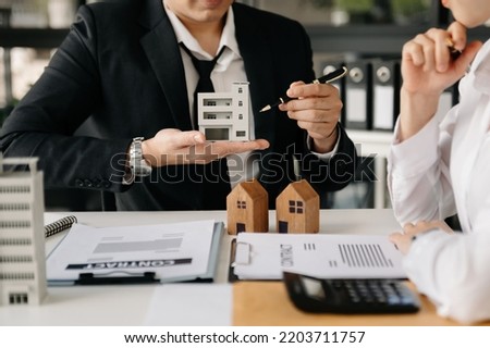 Real estate broker agent presenting and consult to customer to decision making sign insurance form agreement, home model, concerning mortgage loan offer 