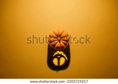 Halloween background concept. Jack O pumpkin angry face shadow. Spooky smiling shadow of an orange pumpkin lantern top view close up, Halloween party design