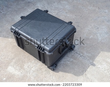 Black case on wheels. Shockproof case for expensive equipment. Concept case for multimedia or sound equipment. Boxing on wheels top view. Protective corps for transporting equipment. Royalty-Free Stock Photo #2203723309
