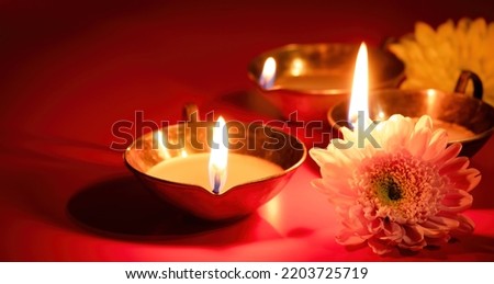 Happy Diwali. Diya oil lamp and flowers on red background. Traditional Hindu celebration. Religious holiday of light. Copy space, banner format. Royalty-Free Stock Photo #2203725719