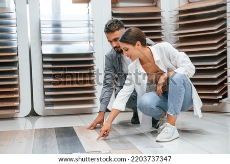 Sitting and choosing parquet. Woman and man is in the store of goods for the home. Royalty-Free Stock Photo #2203737347