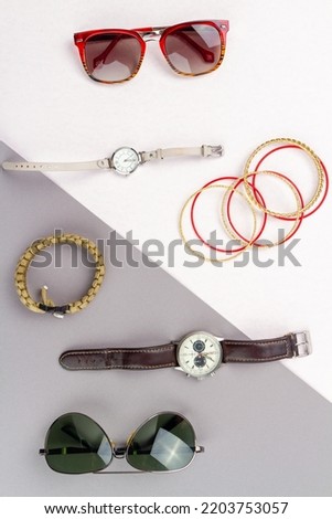Flat lay contrast of mens and womens accessories. Top view glasses with watch and bracelets.