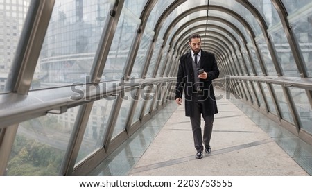 Confident young businessman full body portrait walking at the Defense District. Paris, France. 