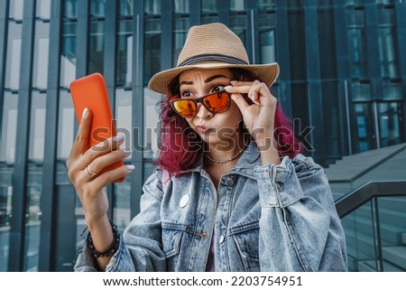 Girl looks at the screen of her phone in surprise and funny. The concept of unexpected virtual communication and shock content