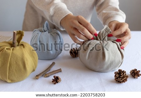 closeup of female hands making fabric pumpkins. Thanksgiving and Halloween decoration. Furoshiki gifts