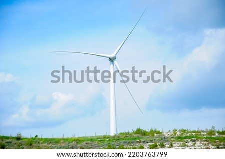 Fleet of power generators in motion. The blades of the wind farm rotate against the sky. The concept of extracting electricity from renewable sources. Wind turbine to generate electricity. Royalty-Free Stock Photo #2203763799