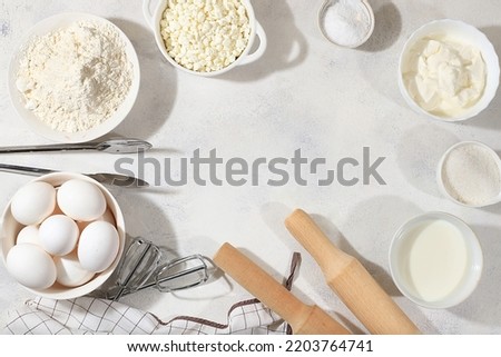 Frame for baking and making cake, bread, confectionery and ingredients for cooking, milk, flour, salt, sugar, eggs and cream on a concrete background with space for text, selective focus, top view