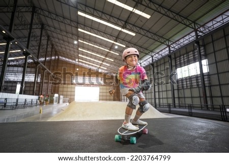 asian child skater or kid girl enjoy fun playing skateboard or smile ride surf skate on wave ramp at indoor skate park by extreme sports to wearing helmet wrist knee support for body safety on summer