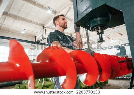 Professional engineer operating machine. Man in uniform is in workstation developing details of agriculture technique.