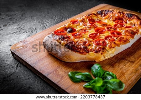 flatbread Pizza with Mozzarella cheese, Tomatoes, pepper, Spices and Fresh Basil. Italian pizza. Pizza Margherita or Margarita on Dark grey black slate background Royalty-Free Stock Photo #2203778437