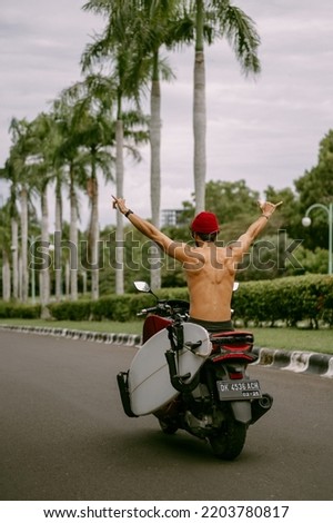 Surfer rides on motorbike with surfboard. Bali island, Indonesia Royalty-Free Stock Photo #2203780817