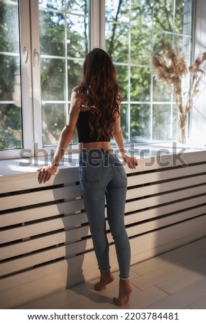 Girl in tight jeans look out the window
 Royalty-Free Stock Photo #2203784481