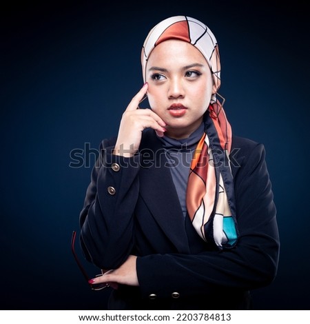 Closeup portrait of a beautiful female Muslim model wearing hijab, a lifestyle apparel for Muslim women isolated on dark grey background. Modern hijab fashion concept.