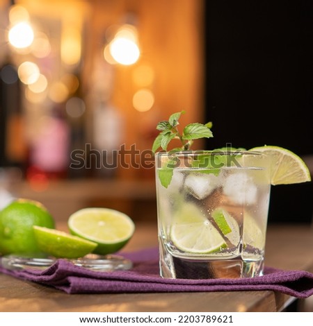 Lime cocktail with mint and ice on the background of the bar. Refreshing alcoholic cocktail.