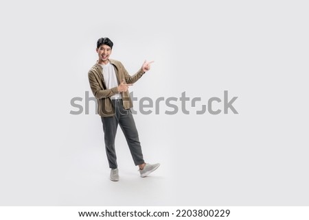 Full length of a handsome asian man pointing out to present something, the smile on his face, his hand gesture and the casual outfit are perfect for the suggestion to copy space. Royalty-Free Stock Photo #2203800229