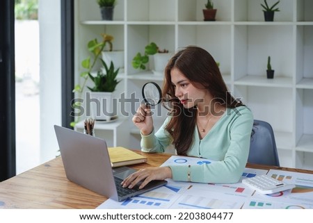 accountant holding a magnifying glass and using a calculator to check financial statements Royalty-Free Stock Photo #2203804477